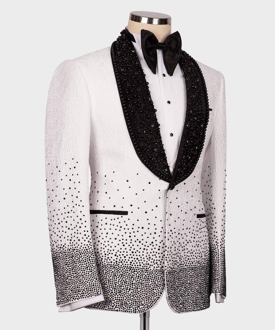 A white tuxedo jacket with a black gradient rhinestone ombre effect at the hem and lapels, styled on a mannequin with a black bow tie and white shirt.