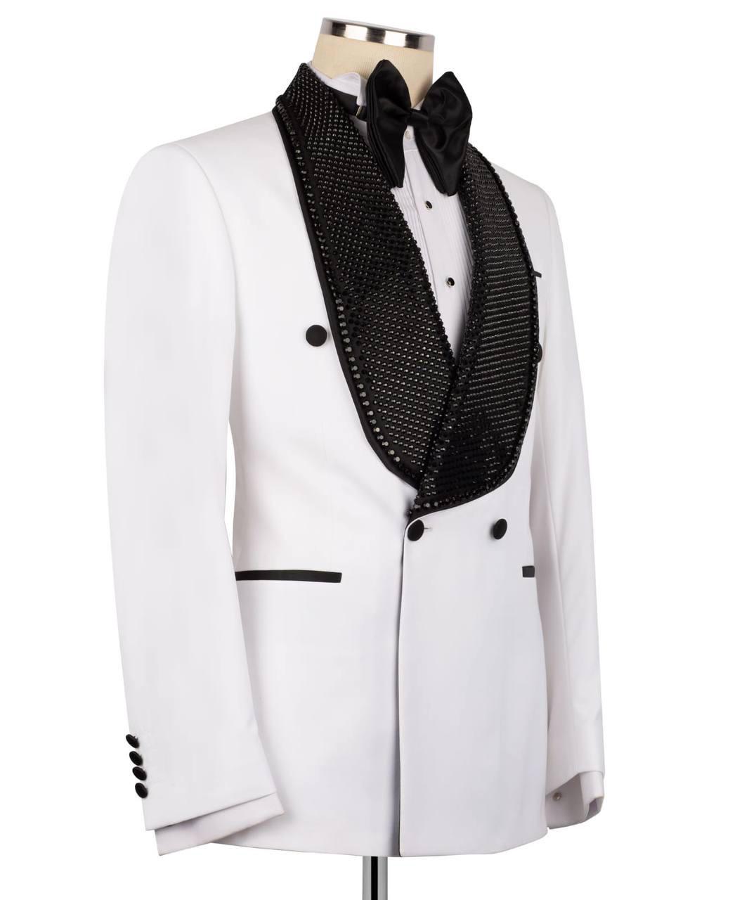 A white tuxedo jacket with a double-breasted front, featuring a black beaded tuxedo lapel, a black bow tie, and black button accents, displayed on a mannequin torso against a white background.