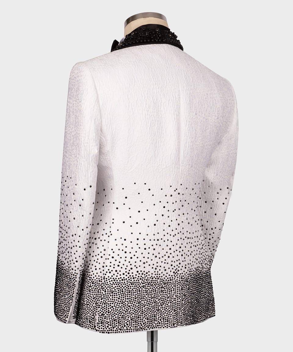 White blazer with black polka dot pattern on a mannequin against a white background
