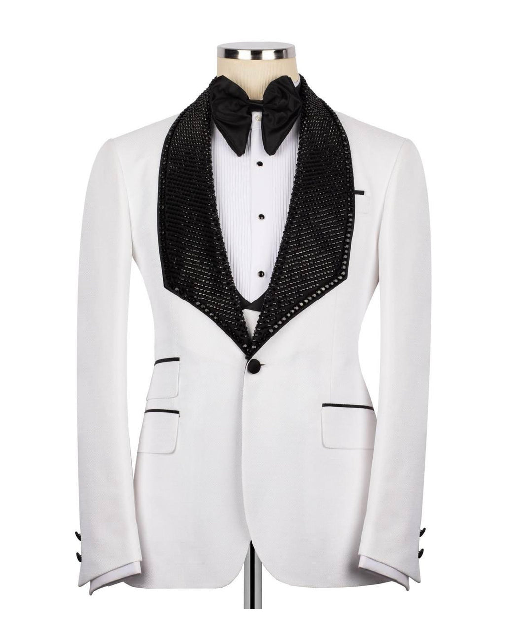A white tuxedo jacket with a black sequined shawl collar, styled on a mannequin with a white pleated shirt, black bow tie, and black vest.