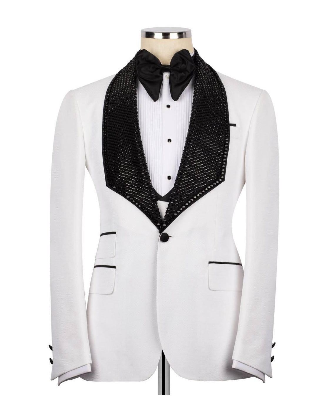 A white tuxedo jacket with a black sequined shawl collar, styled on a mannequin with a white pleated shirt, black bow tie, and black vest.