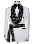 A white textured tuxedo jacket displayed on a mannequin with a black bow tie, white dress shirt, and a large black embellished shawl with a matching patterned waist tie.