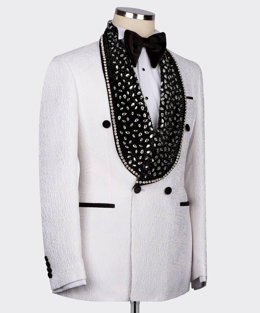A white textured tuxedo jacket displayed on a mannequin with a white shirt, black bow tie, and a prominent black beaded cowl necklace with silver rhinestone trim.