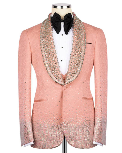 A peach-colored tuxedo jacket embellished with sparkling rhinestones, styled on a mannequin with a white pleated shirt, black bow tie, and a matching rhinestone-trimmed collar.