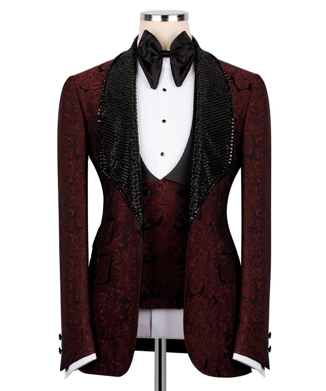 A men's tuxedo jacket with a dark burgundy and black damask pattern, featuring wide black beaded shawl lapels, styled on a mannequin with a white pleated shirt, black bow tie, and matching waistcoat.