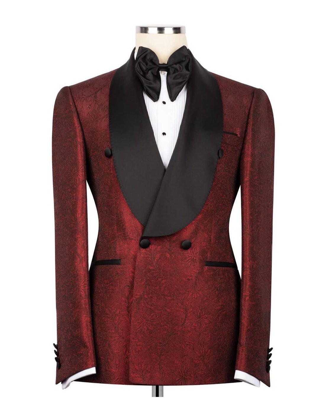 A men's double-breasted tuxedo jacket in a deep red brocade fabric with black satin peak lapels, styled on a mannequin with a black bow tie and white dress shirt against a plain white background.