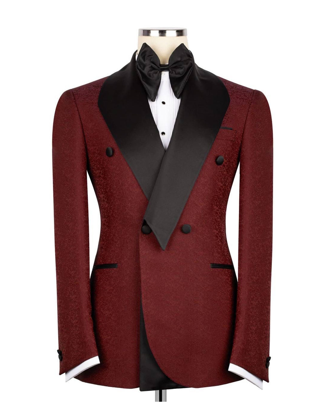 A men's double-breasted tuxedo jacket in a textured burgundy fabric with black satin peak lapels, displayed on a mannequin torso with a black bow tie, white dress shirt, and white cufflinks against a plain white background.