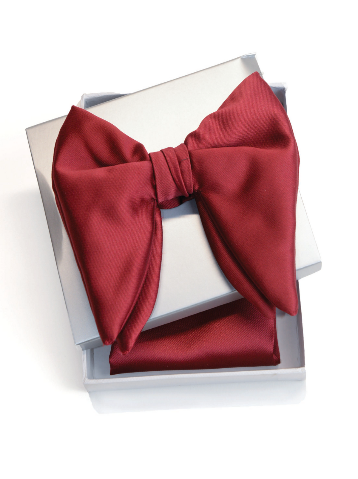 A deep red satin bow tie presented in an open white gift box with a matching red pocket square, photographed on a clean white background.