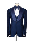 A men's formal tuxedo jacket displayed on a mannequin torso, featuring a textured navy blue body, satin peak lapels, a matching navy blue bow tie, white dress shirt, and a navy blue vest.