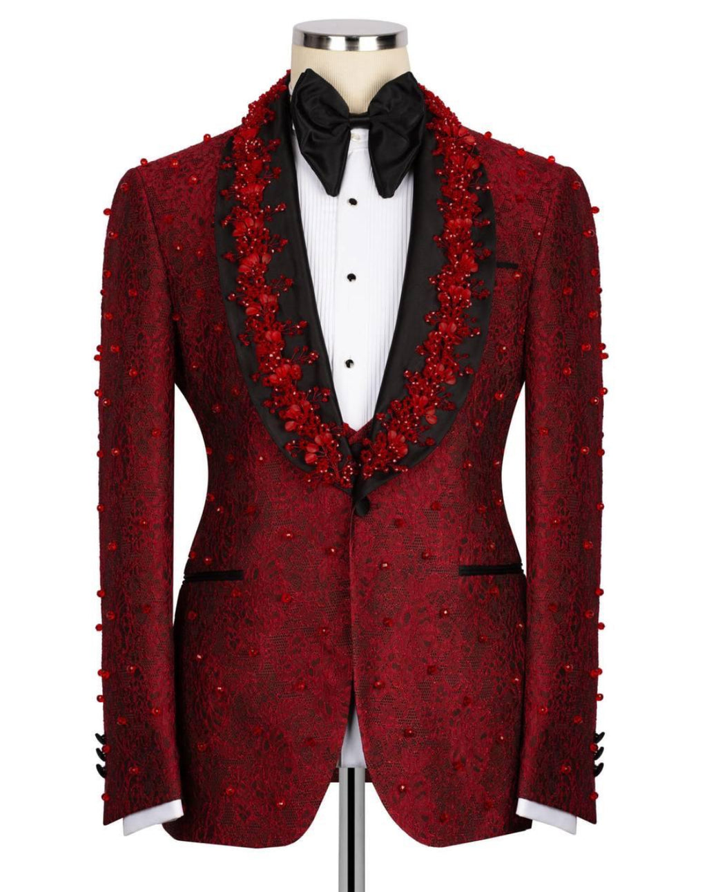 A red patterned tuxedo jacket with red floral bead embellishments, styled on a mannequin with a black bow tie and white shirt against a white background.