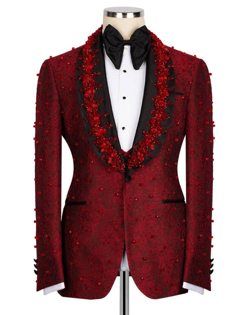 A red patterned tuxedo jacket with red floral bead embellishments, styled on a mannequin with a black bow tie and white shirt against a white background.