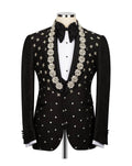 A black tuxedo jacket with ornate silver and gold star-patterned beadwork and embroidery, styled on a mannequin with a white shirt, black bow tie, and white cufflinks.