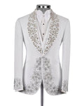 A white tuxedo jacket with elaborate silver and gold floral beadwork on the shawl collar and front panels, displayed on a mannequin with a white shirt and bow tie against a light gray background.