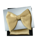 A gold satin bow tie displayed on top of a matching gold pocket square inside an open black gift box with a white insert, photographed on a plain white background.