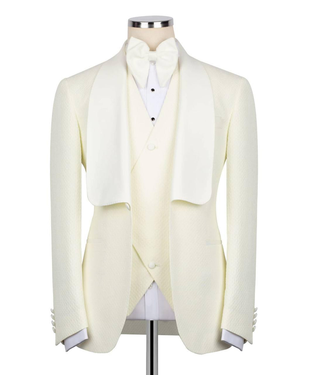 An ivory formal tuxedo jacket with wide shawl lapels, worn by a dress form and styled with a matching bow tie, white shirt, and cream waistcoat against a plain white background.