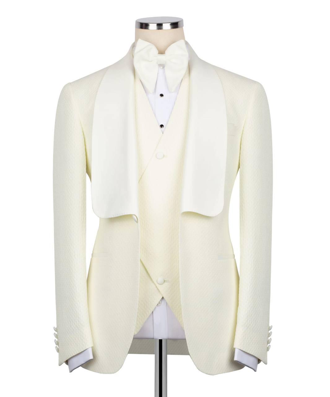 An ivory formal tuxedo jacket with wide shawl lapels, worn by a dress form and styled with a matching bow tie, white shirt, and cream waistcoat against a plain white background.