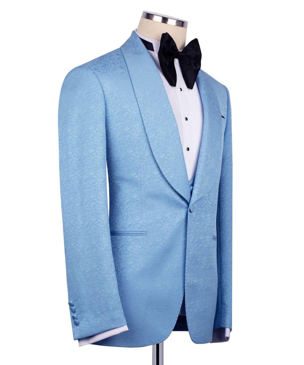 A light blue textured tuxedo jacket displayed on a mannequin torso, styled with a white dress shirt, black bow tie, and black trousers against a plain white background.