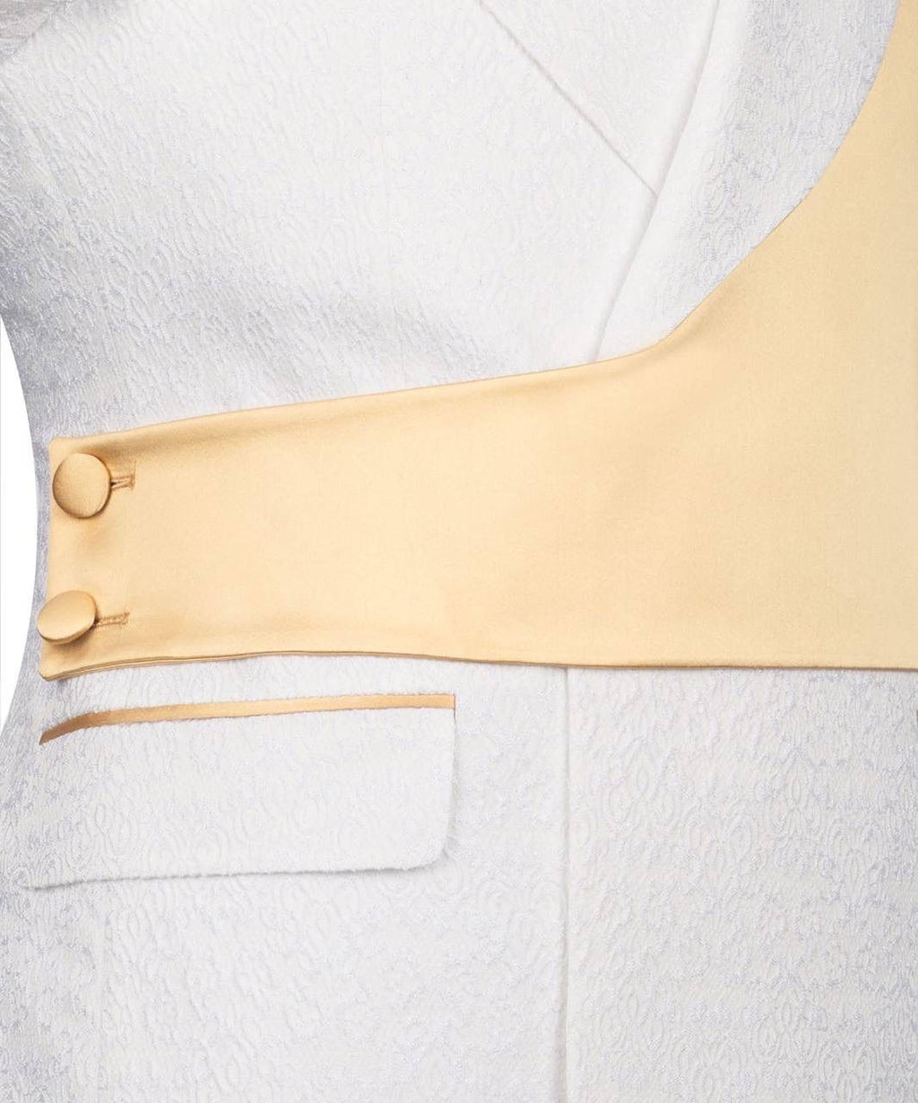 Close-up detail of a white textured jacket with a wide beige lapel and two gold buttons on the sleeve.