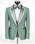 A sage green men's tuxedo jacket with satin peak lapels in a matching sage green and white, styled on a mannequin with a white dress shirt, a matching sage green bow tie, and a matching green vest.