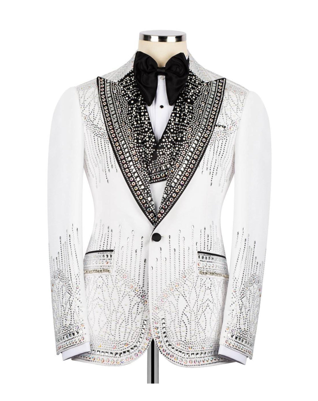 A white tuxedo jacket embellished with intricate black beading and sequins, styled on a mannequin with a black bow tie and white shirt against a plain white background.