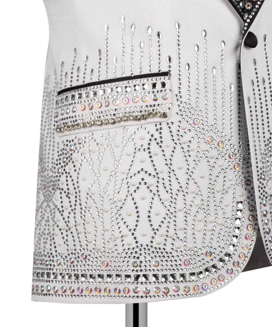 Close-up of a white embellished garment featuring intricate silver rhinestone and bead embroidery, a decorative pocket, and iridescent crystal accents.