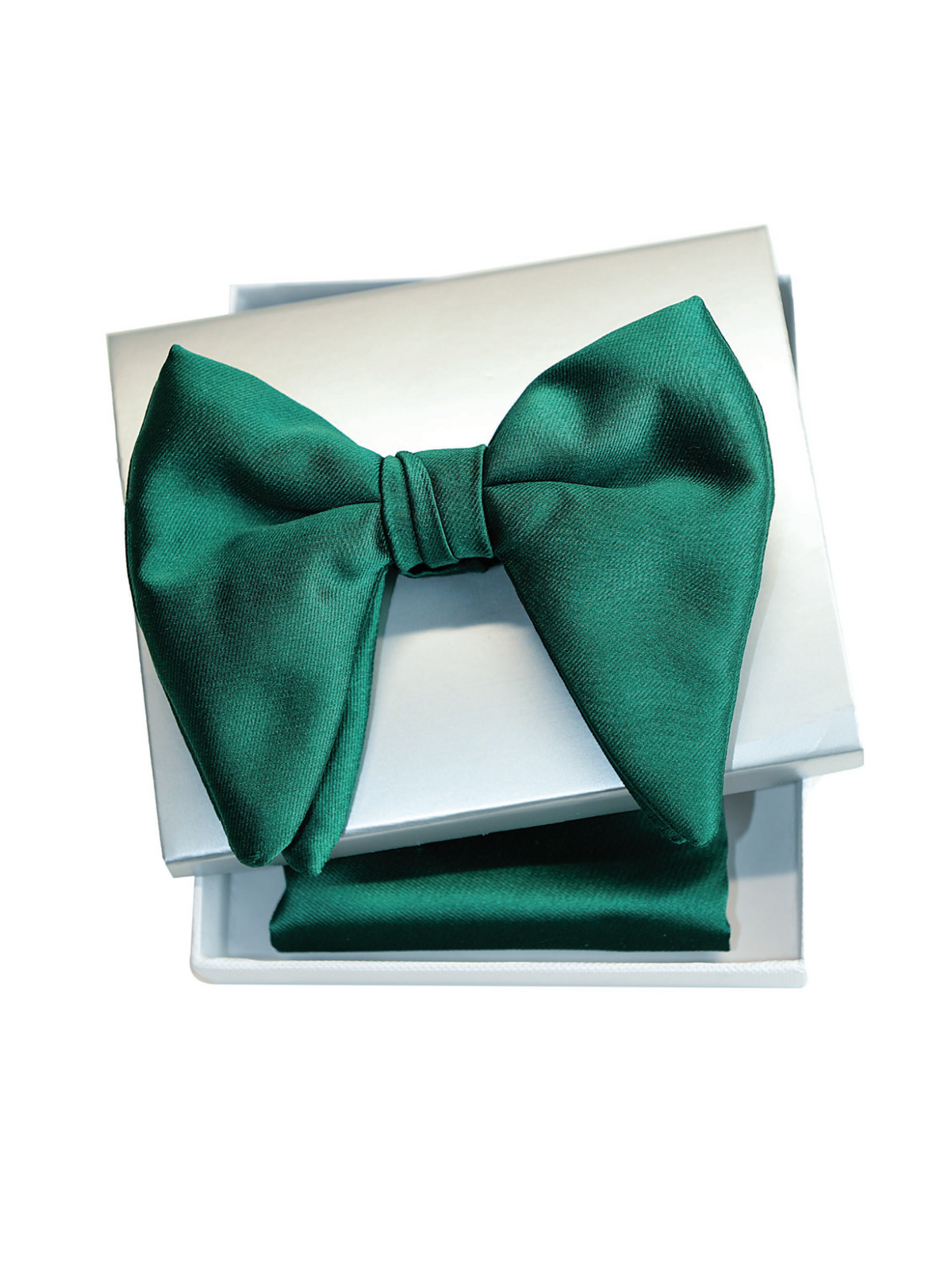A dark emerald green satin bow tie presented in an open white gift box with a matching green pocket square underneath, shot against a solid white background.