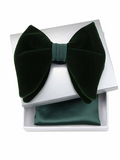 A dark forest green velvet bow tie presented on top of an open white gift box, with a matching green satin pocket square visible inside the box.