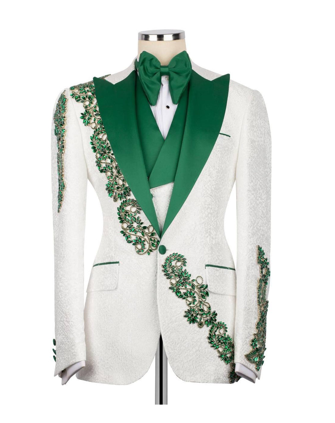 A white textured tuxedo jacket with vibrant green satin lapels, a matching green bow tie, and intricate green floral embroidery running down the front and sleeves, displayed on a mannequin against a white background.