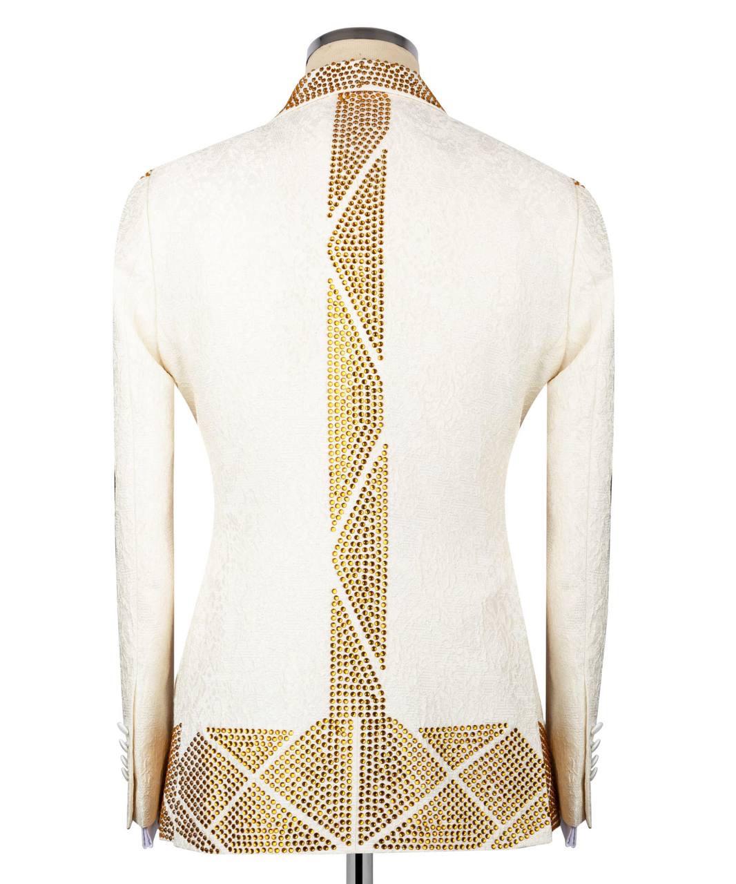 An off-white textured blazer shown from the back on a mannequin, featuring prominent gold rhinestone geometric patterns running down the center back and across the lower hem.