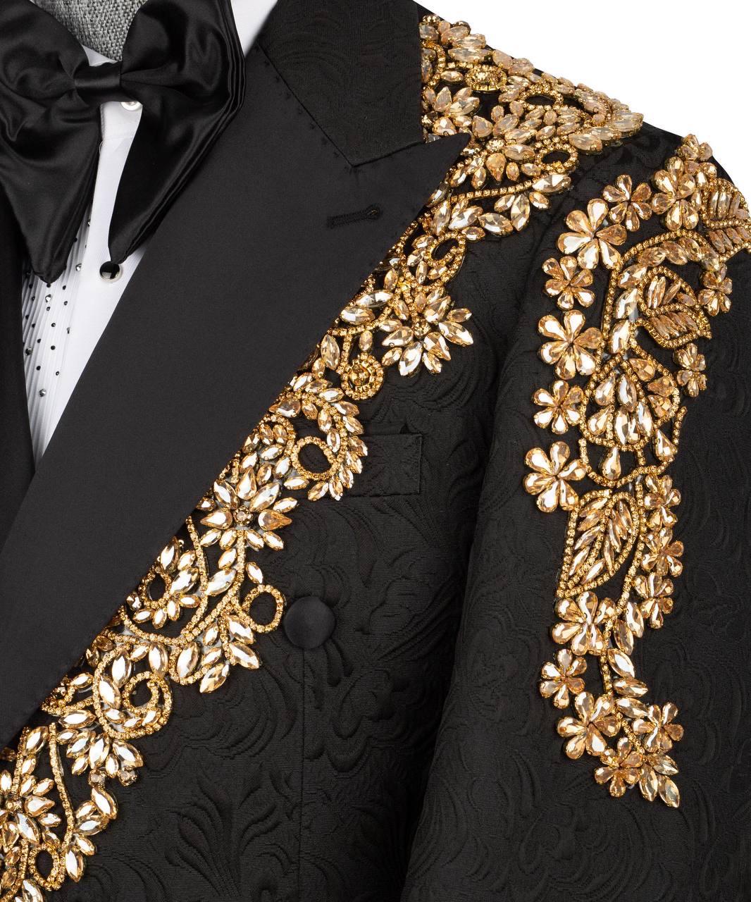 Close-up of a black tuxedo jacket with ornate gold floral embroidery and beadwork, styled with a black bow tie and white dress shirt.
