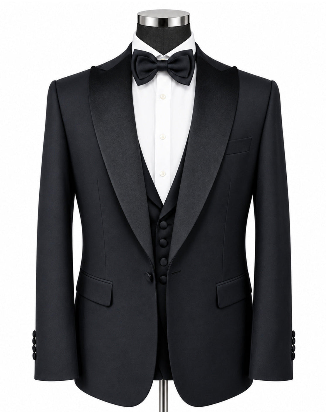 A black tuxedo jacket displayed on a mannequin torso with a white dress shirt, black bow tie, black vest, and a silver stand against a plain white background.