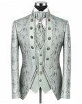 A formal menswear set on a mannequin, featuring a light sage green and gray paisley brocade jacket, matching vest, tie, and high collar with ornate silver-tone buttons.