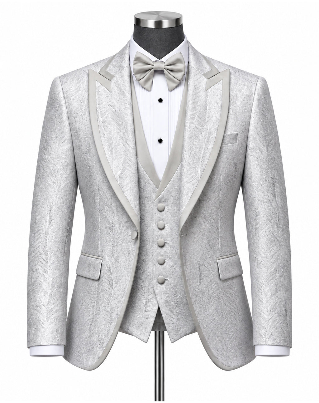 A light silver-gray three-piece tuxedo set with a subtle textured pattern, featuring a jacket with satin peak lapels, a matching vest, a white pleated shirt, a matching bow tie, and a pocket square, displayed on a mannequin.