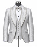 A light silver-gray three-piece tuxedo set with a subtle textured pattern, featuring a jacket with satin peak lapels, a matching vest, a white pleated shirt, a matching bow tie, and a pocket square, displayed on a mannequin.