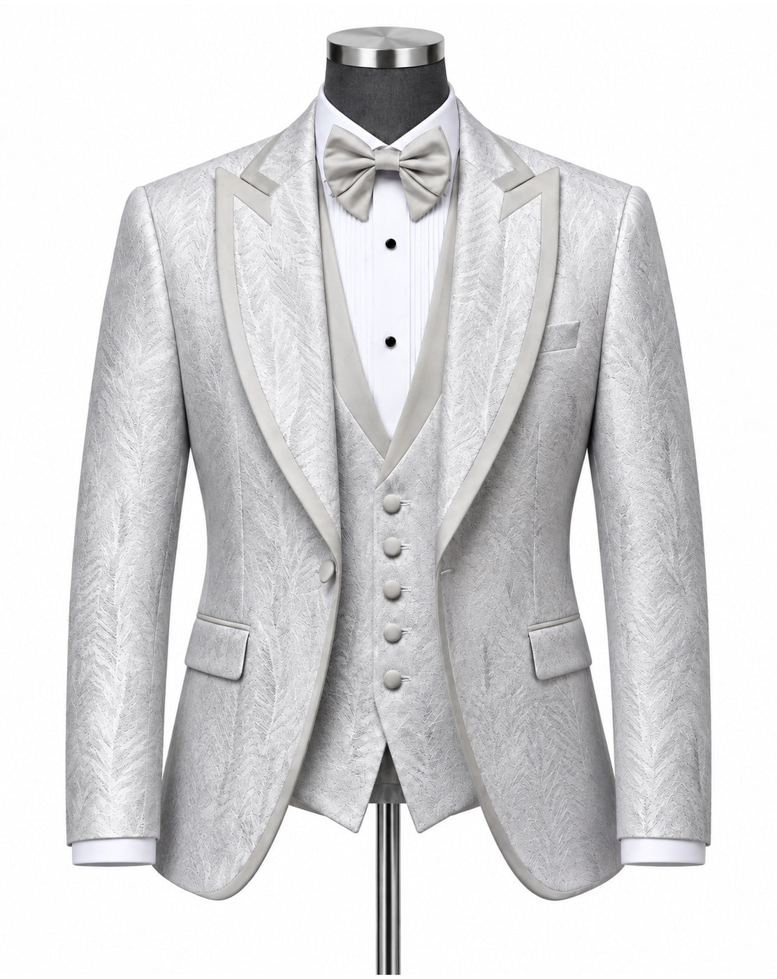 A light silver-gray three-piece tuxedo set with a subtle textured pattern, featuring a jacket with satin peak lapels, a matching vest, a white pleated shirt, a matching bow tie, and a pocket square, displayed on a mannequin.