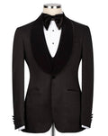 A black tuxedo jacket with a satin peak lapel, displayed on a mannequin torso with a white dress shirt, black bow tie, and matching vest against a light gray background.