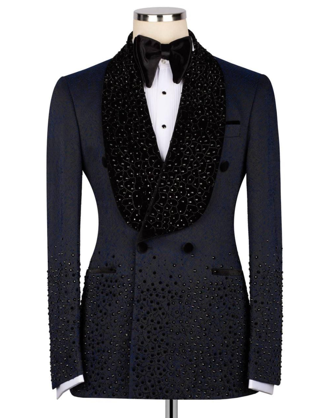 A black double-breasted tuxedo jacket embellished with sparkling rhinestones, styled on a mannequin with a white dress shirt, black bow tie, and a large black beaded collar.