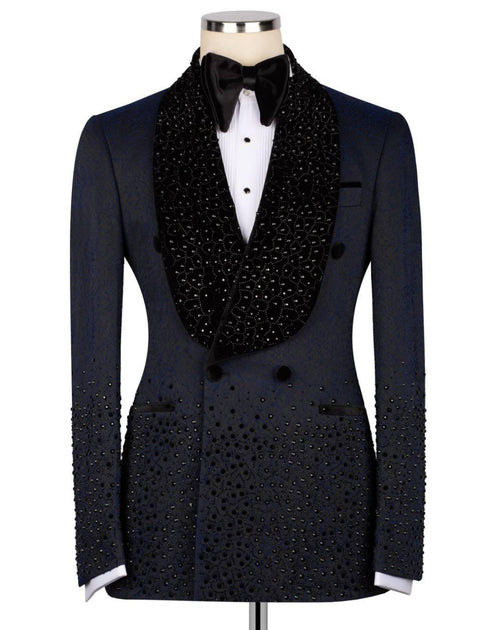 A black double-breasted tuxedo jacket embellished with sparkling rhinestones, styled on a mannequin with a white dress shirt, black bow tie, and a large black beaded collar.
