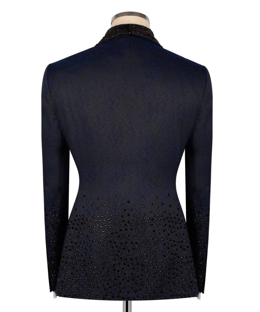 A dark navy blue fitted jacket displayed on a mannequin from the back, featuring textured fabric, a beaded black collar, and a dense pattern of small black beads along the lower back and sleeves.
