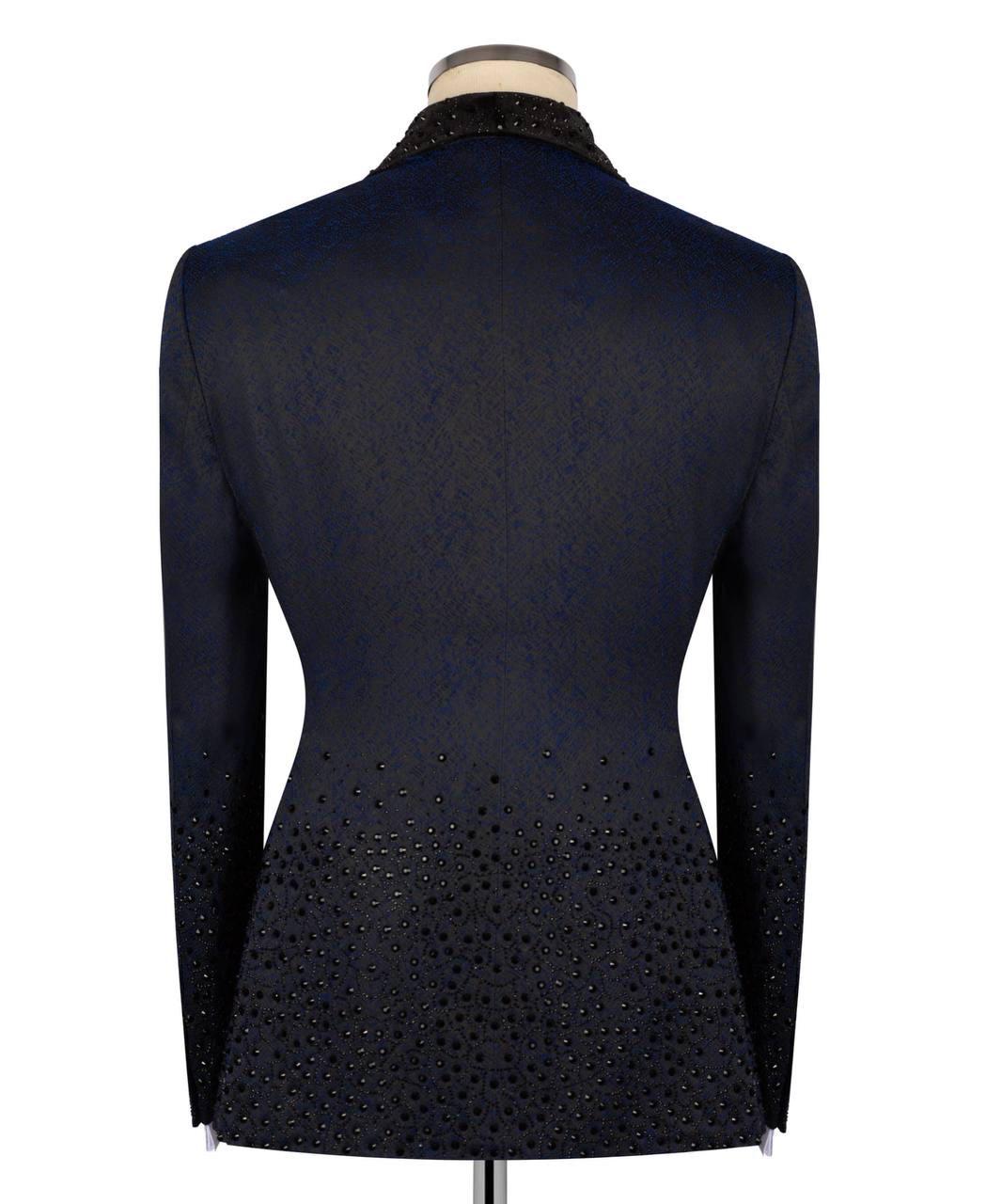 A dark navy blue fitted jacket displayed on a mannequin from the back, featuring textured fabric, a beaded black collar, and a dense pattern of small black beads along the lower back and sleeves.