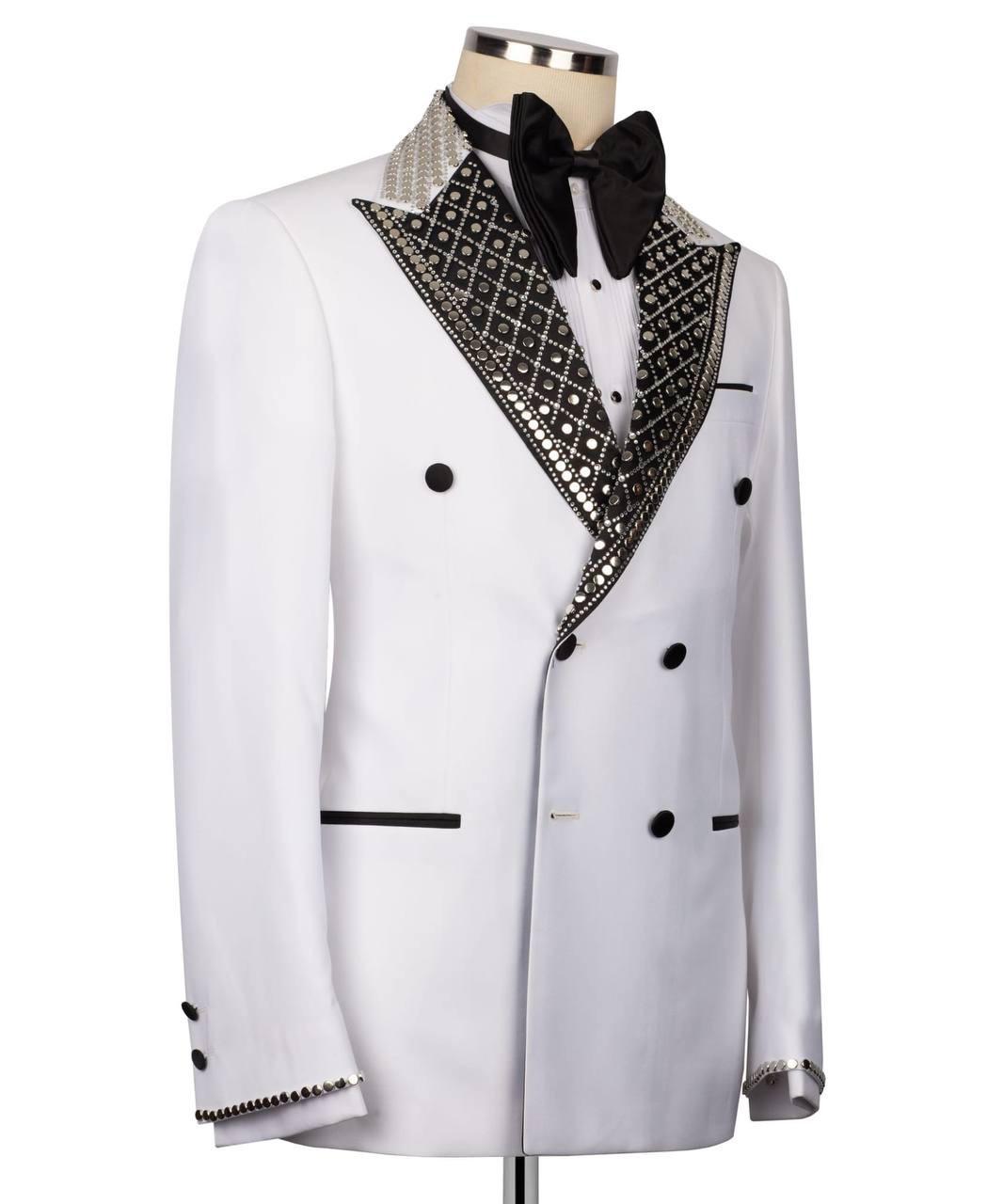 A white double-breasted tuxedo jacket with black buttons, a black bow tie, and ornate black-and-silver patterned lapels, displayed on a mannequin against a white background.