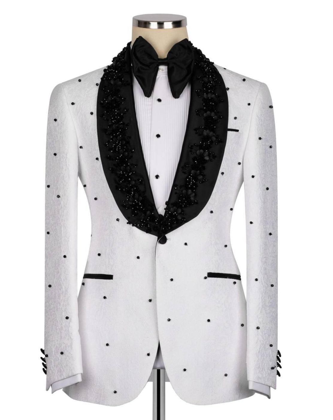 A white tuxedo jacket with black polka dots and black beaded shawl collar, styled on a mannequin with a black bow tie and white shirt.