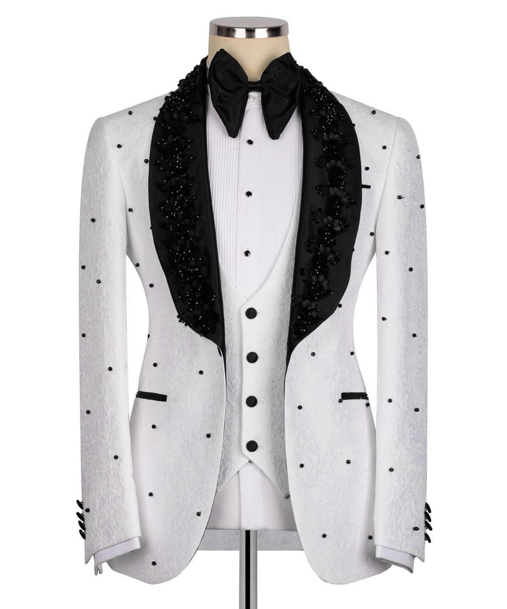 A white tuxedo jacket with black polka dots and black beaded lapels, styled on a mannequin with a white pleated vest, black bow tie, and black satin collar.