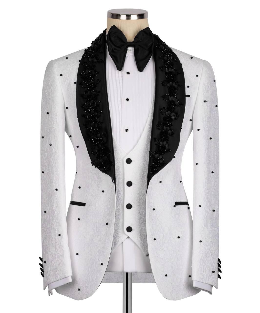 A white tuxedo jacket with black polka dots and black beaded lapels, styled on a mannequin with a white pleated vest, black bow tie, and black satin collar.