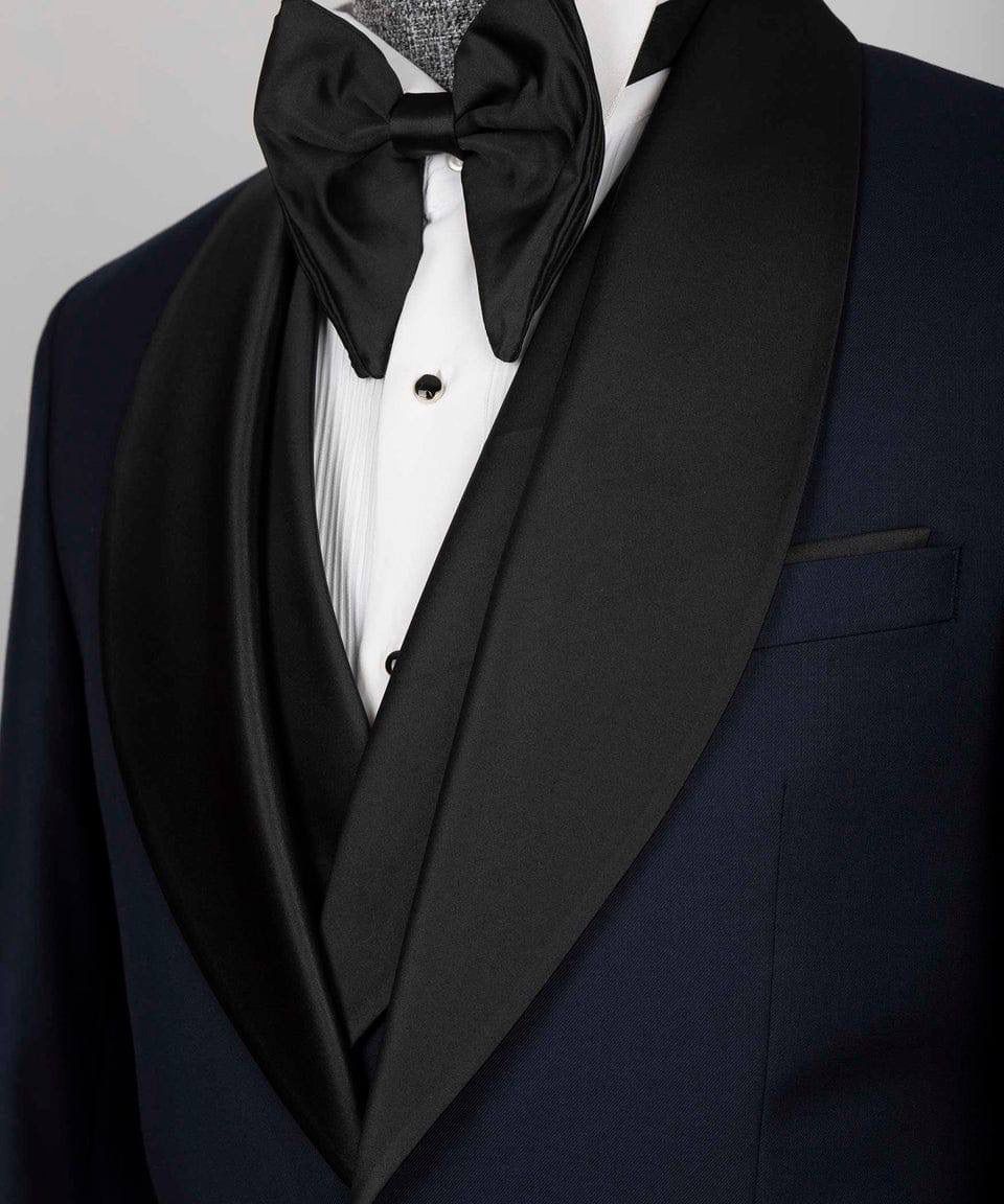 Black tuxedo with a large bow tie on a plain background