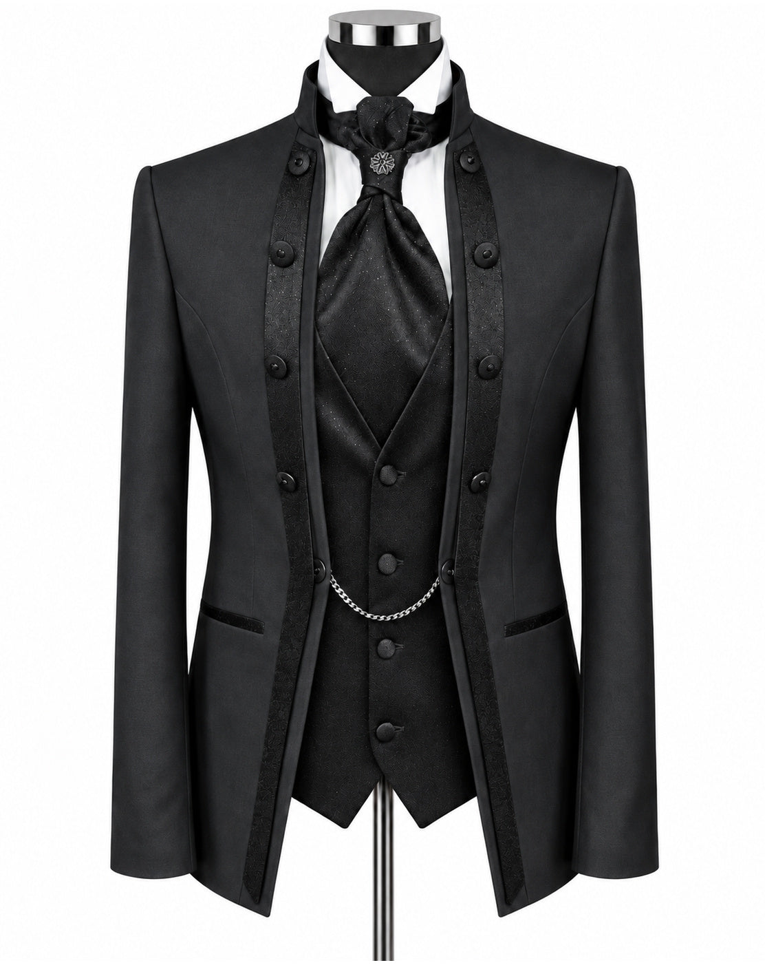 A black formal men's suit set displayed on a mannequin, featuring a double-breasted jacket with satin lapels, a matching vest, a white shirt, a black tie, and a silver chain detail.