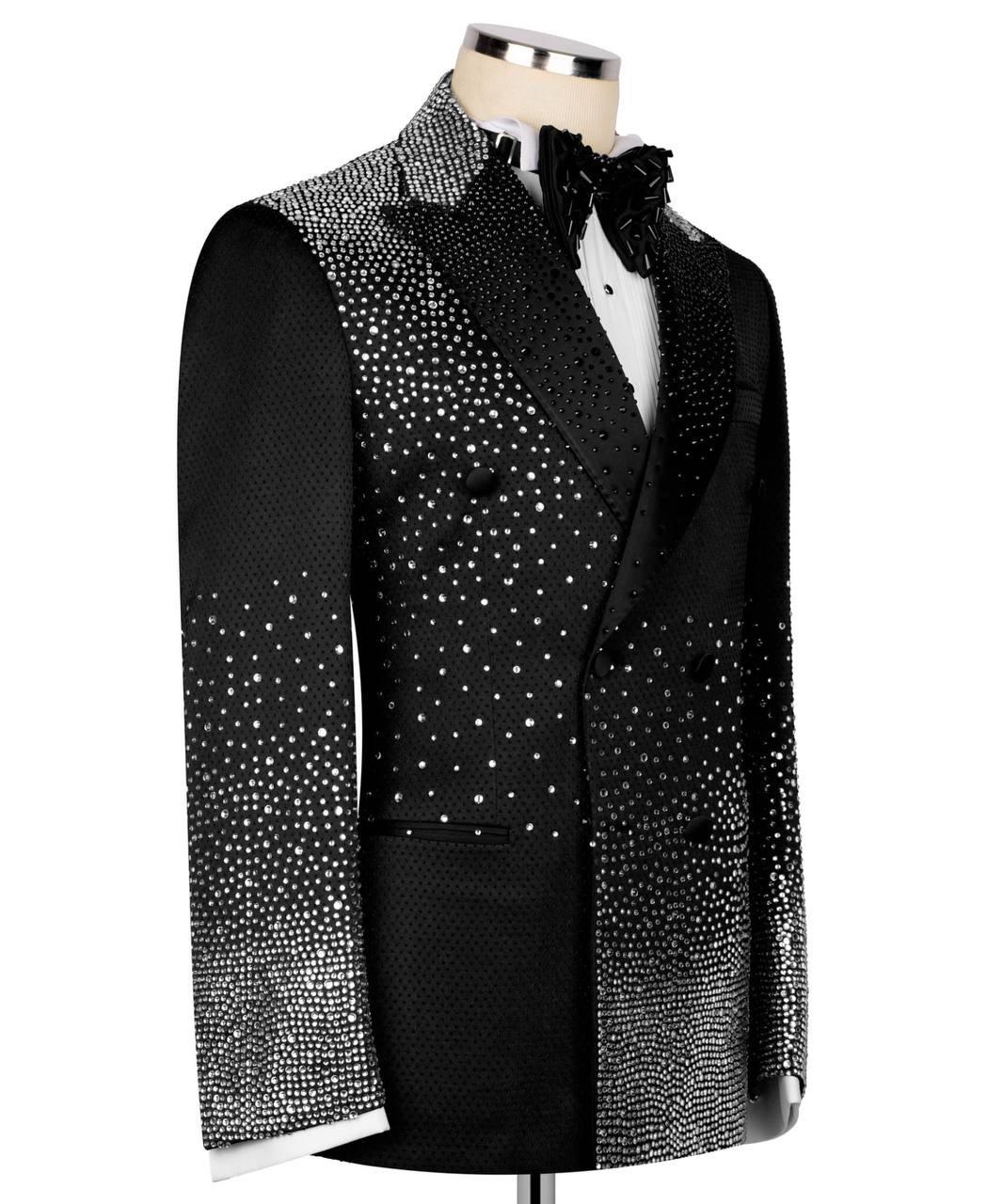 A men's black tuxedo jacket with sparkling silver rhinestone embellishments, styled on a mannequin with a white shirt and black bow tie against a plain white background.