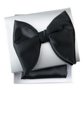 A pre-tied black satin bow tie presented on top of its white gift box, with a matching black pocket square folded underneath.