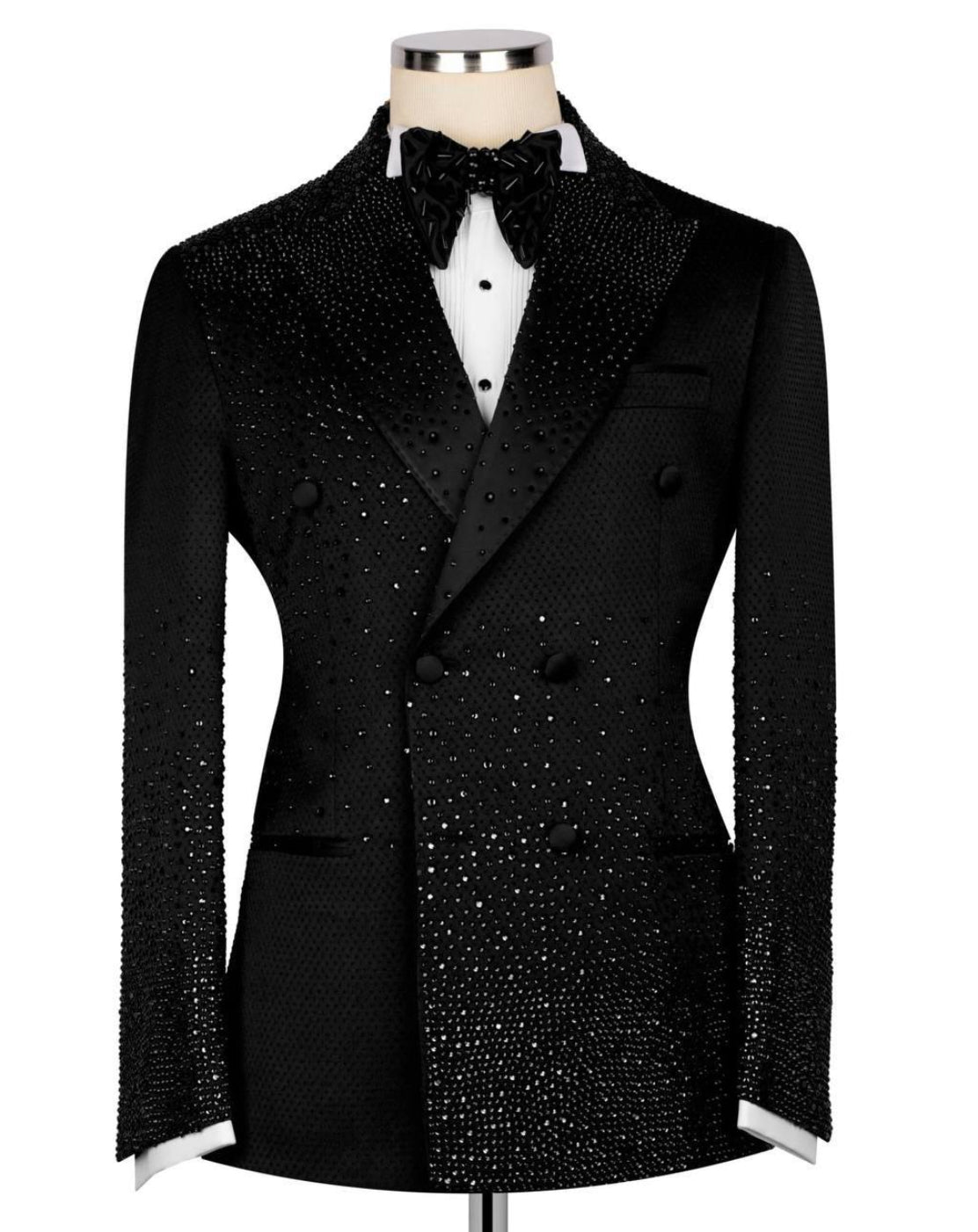 A black double-breasted tuxedo jacket embellished with sparkling rhinestones, displayed on a mannequin with a white dress shirt and black bow tie against a plain white background.