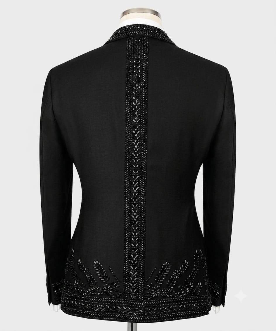 Black long-sleeve blazer shown from the back on a mannequin, featuring ornate beaded and embroidered detailing running down the center back and along the hem.